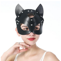 A woman wearing a black faux-leather cat mask with pointed ears and silver rivet details, posed against a solid white background.